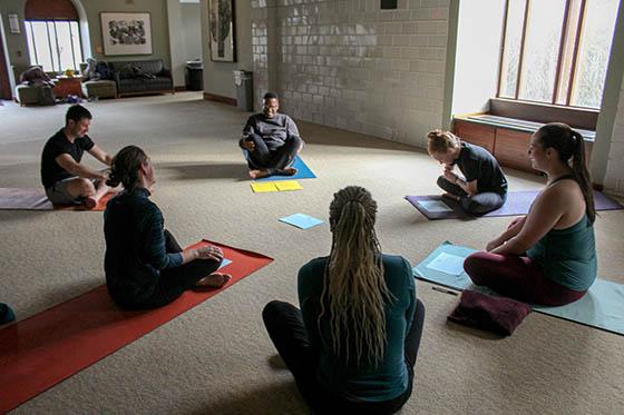 Photo of people sitting in a circle on yoga mats, in a group meditation.